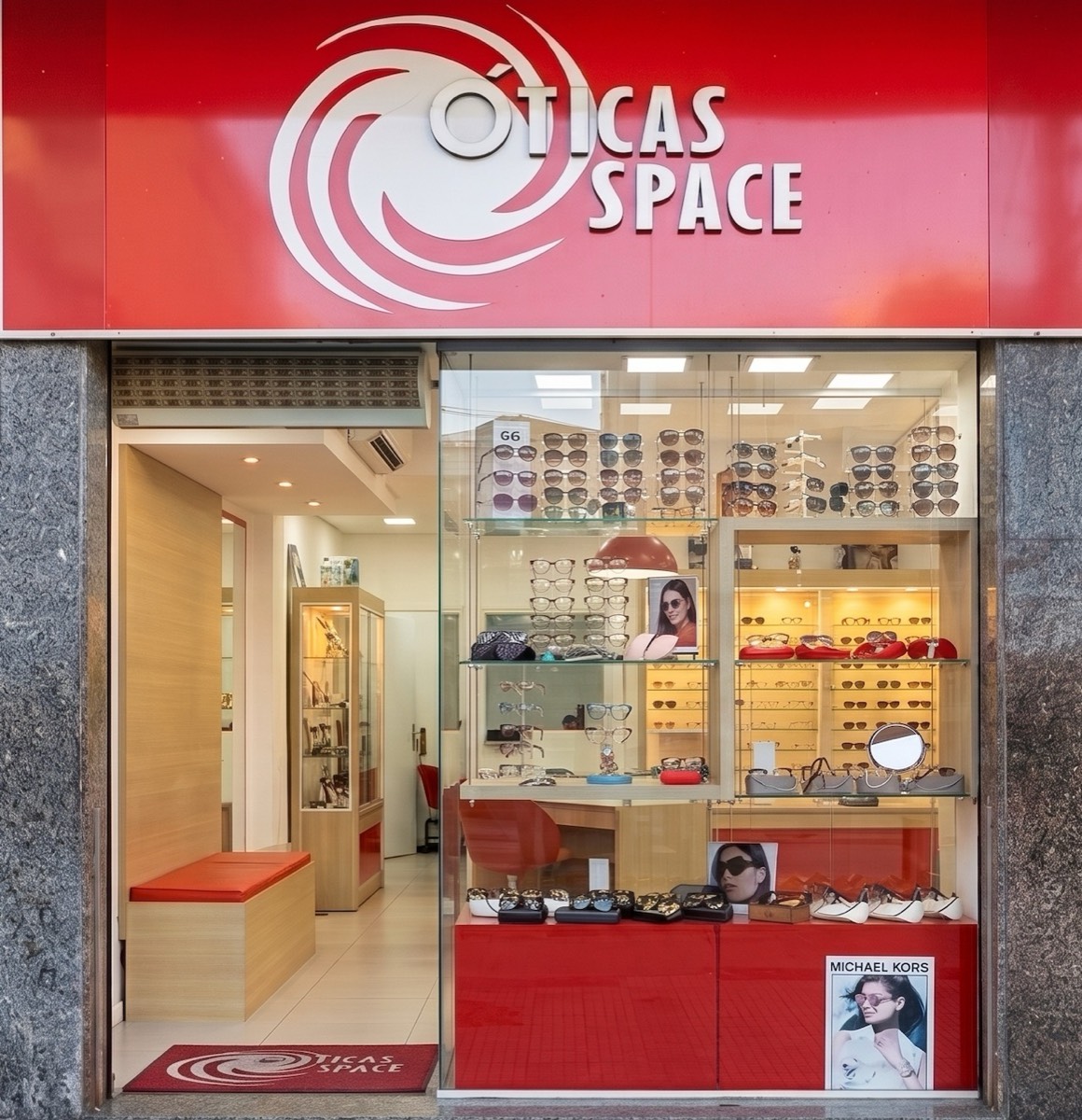 Fachada vermelha da Ótica Space com vitrine de óculos